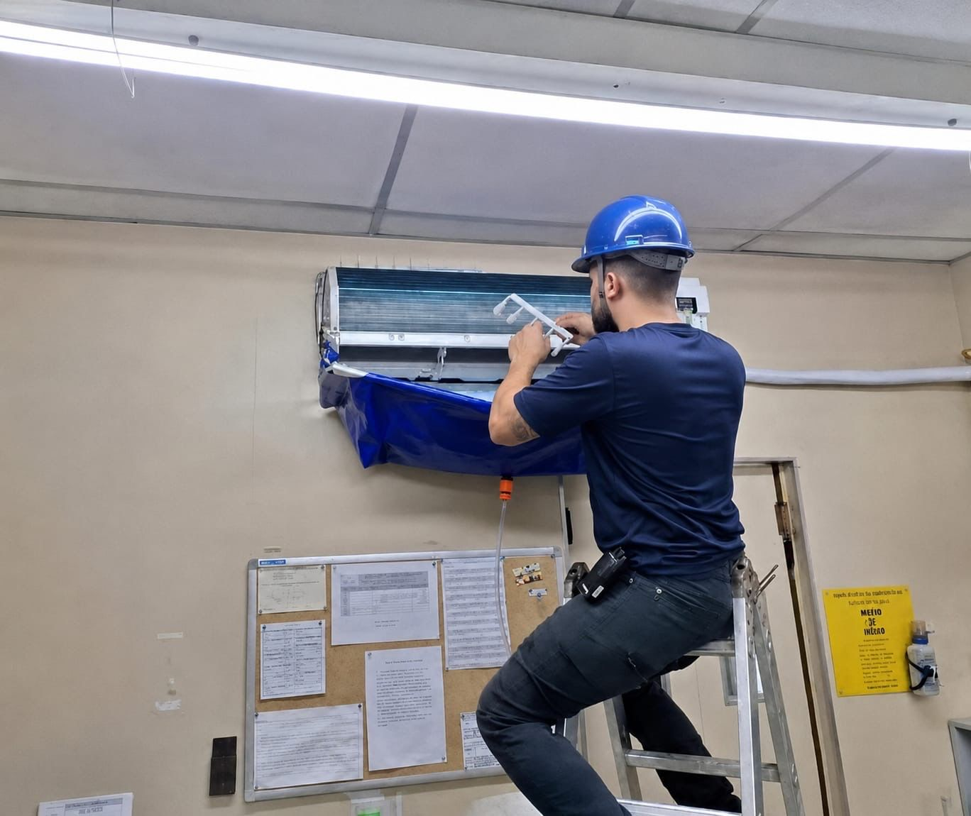 Técnico realizando manutenção em ar-condicionado de ambiente empresarial